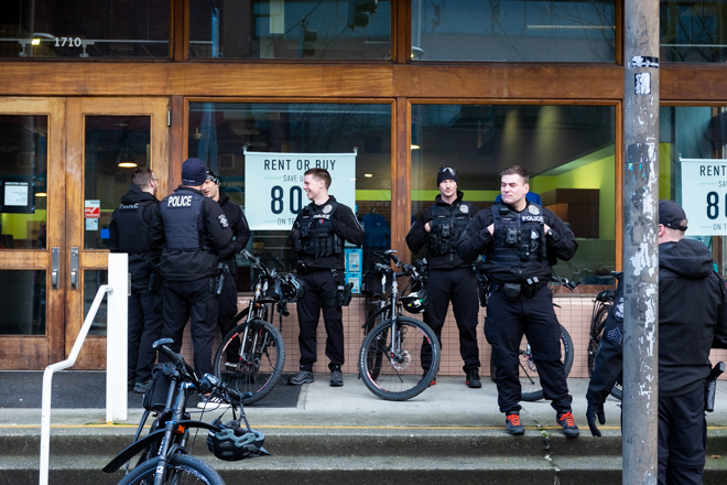 Seven police stand in front of Seattle Central's bookstore, talking.